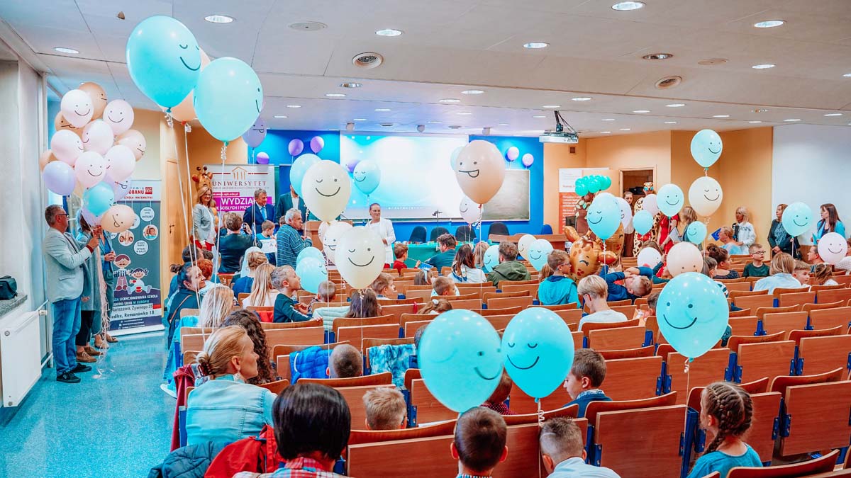 Dzieci na sali konferencyjnej z balonami w dłoniach