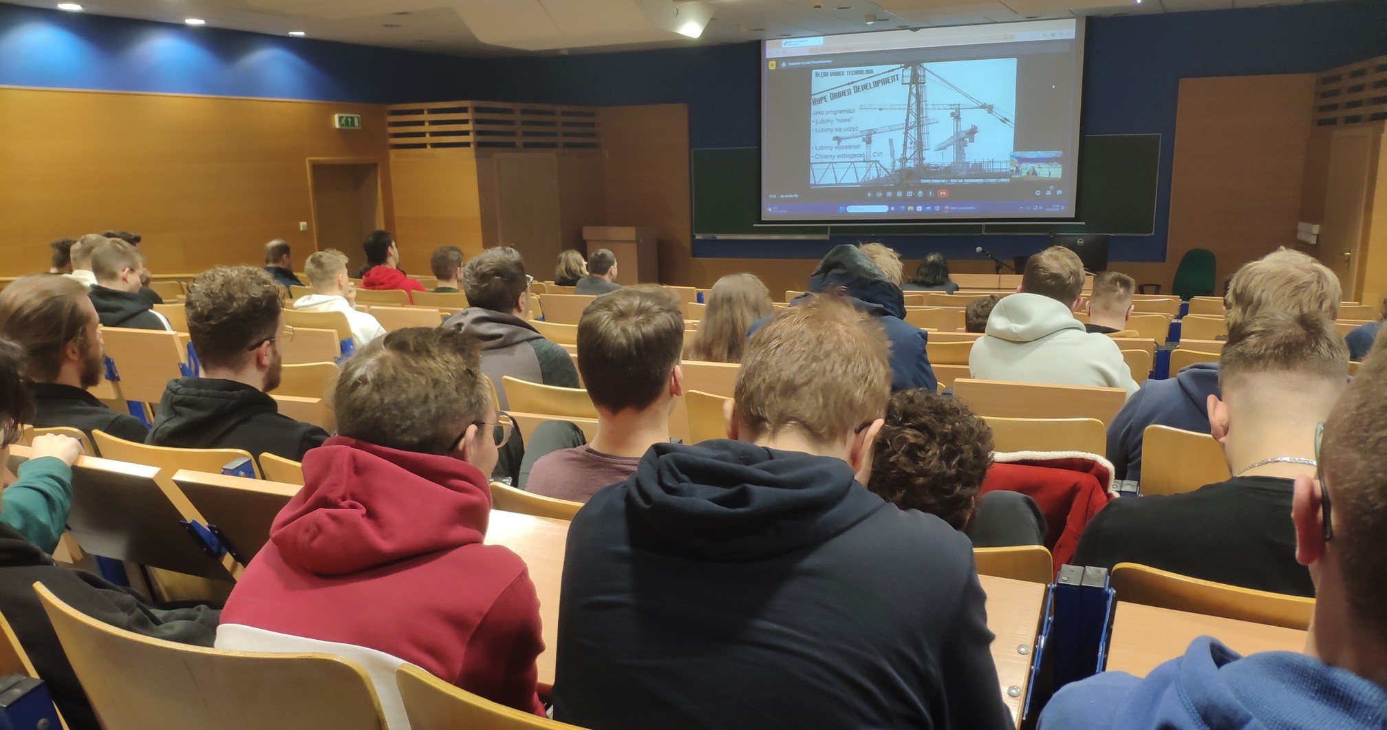 Uczestnicy szkolenia w auli wykładowej oglądają prelekcję na dużym ekranie